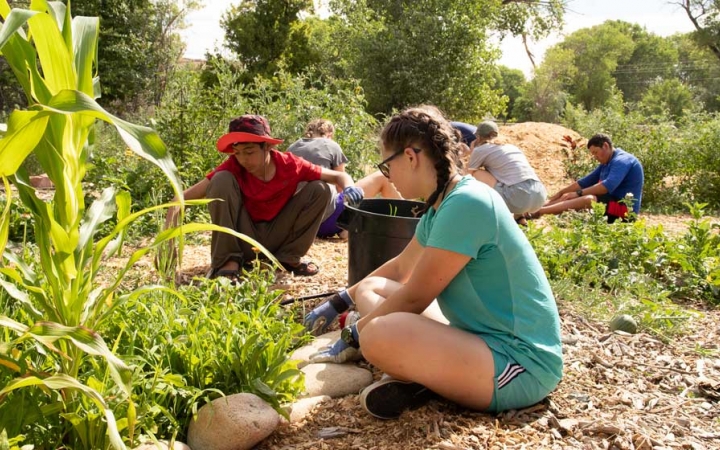 Students work in a garden during a service project with outward bound